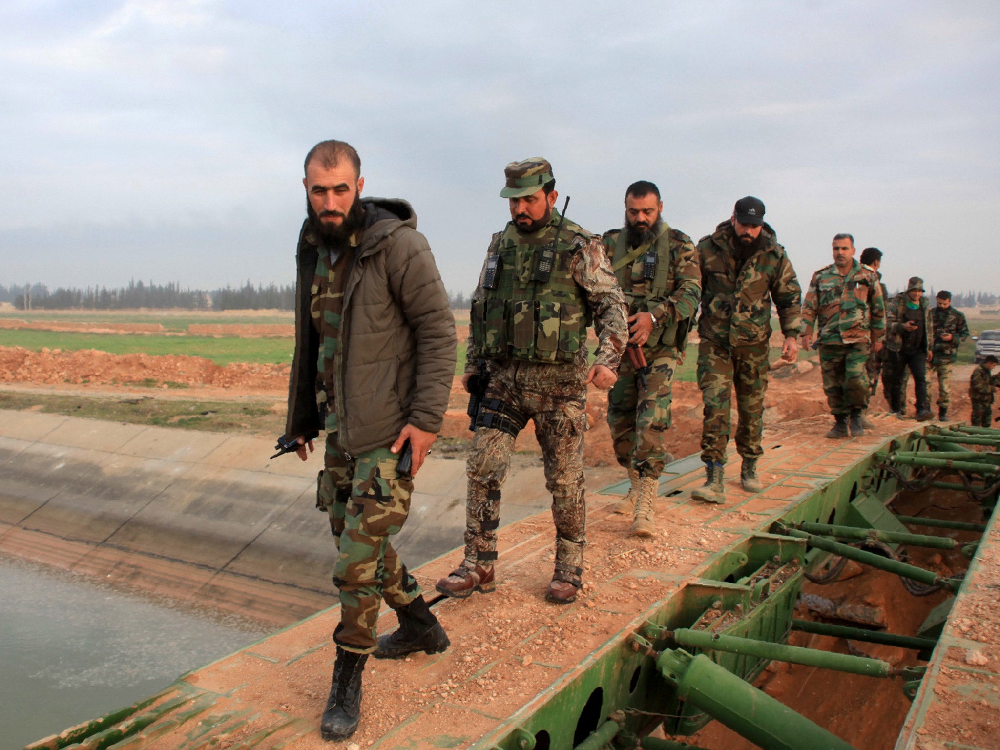 Syrian government forces cross a retractable military bridge on the outskirts of Aleppo