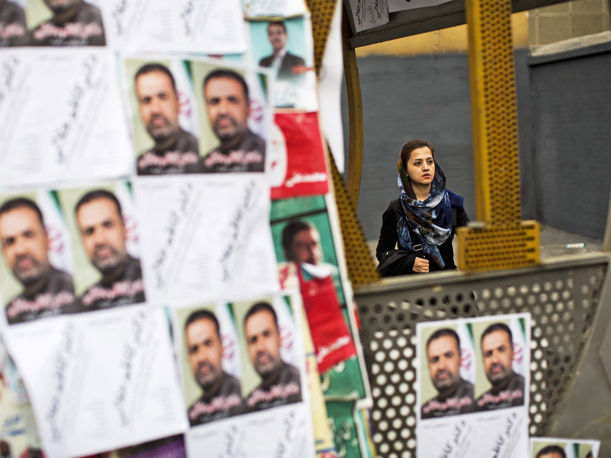 A woman walks past electoral posters for the upcoming elections in Tehran