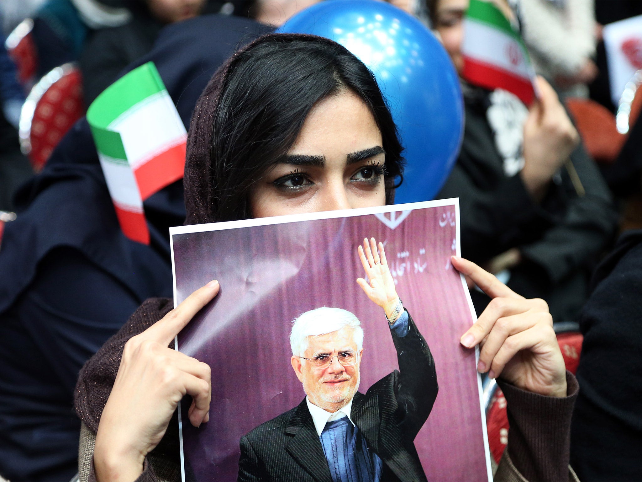 An Iranian woman holds up a poster of Mohammad Reza Aref, a prominent reformist candidate