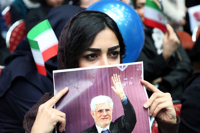 An Iranian woman holds up a poster of Mohammad Reza Aref, a prominent reformist candidate