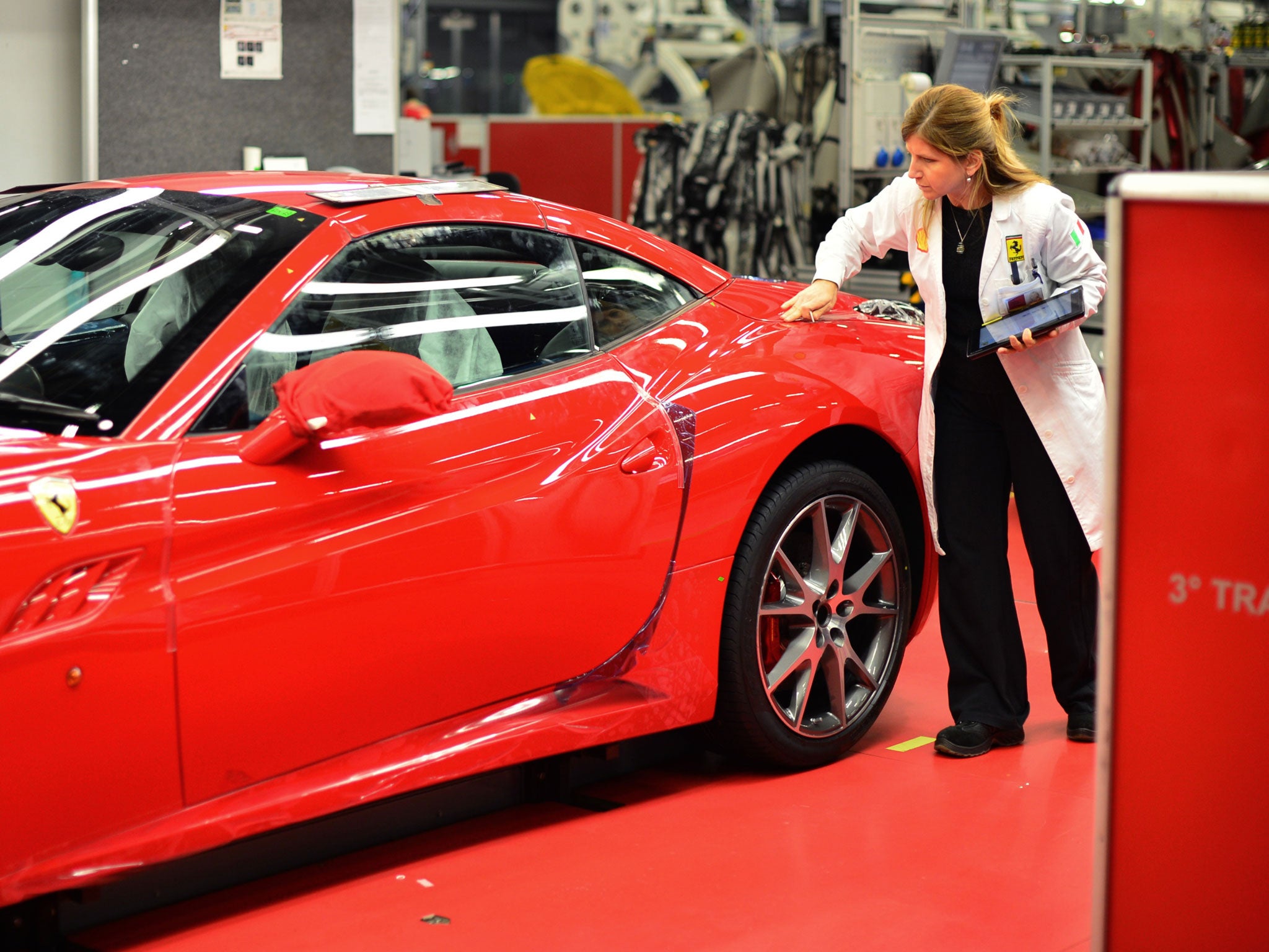 An employee checks a car at the end of the assembly line