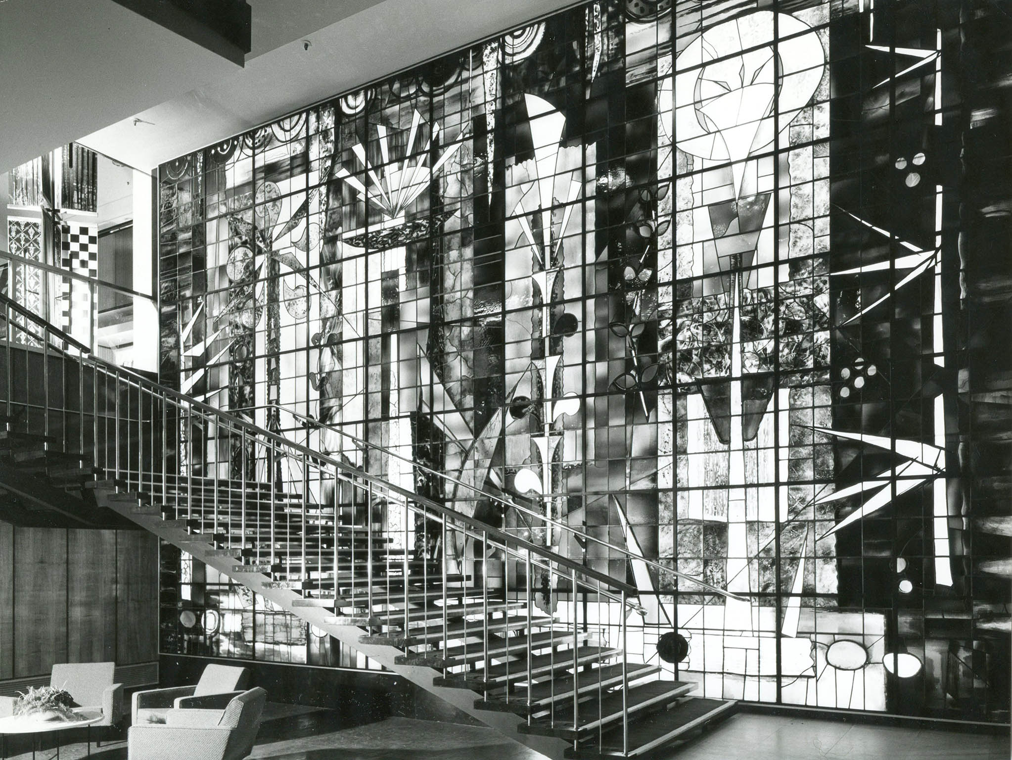 Photograph of the stairwell of Sanderson House featuring Composition, 1960. Stained glass, executed by Patrick Reyntiens to Piper’s designs