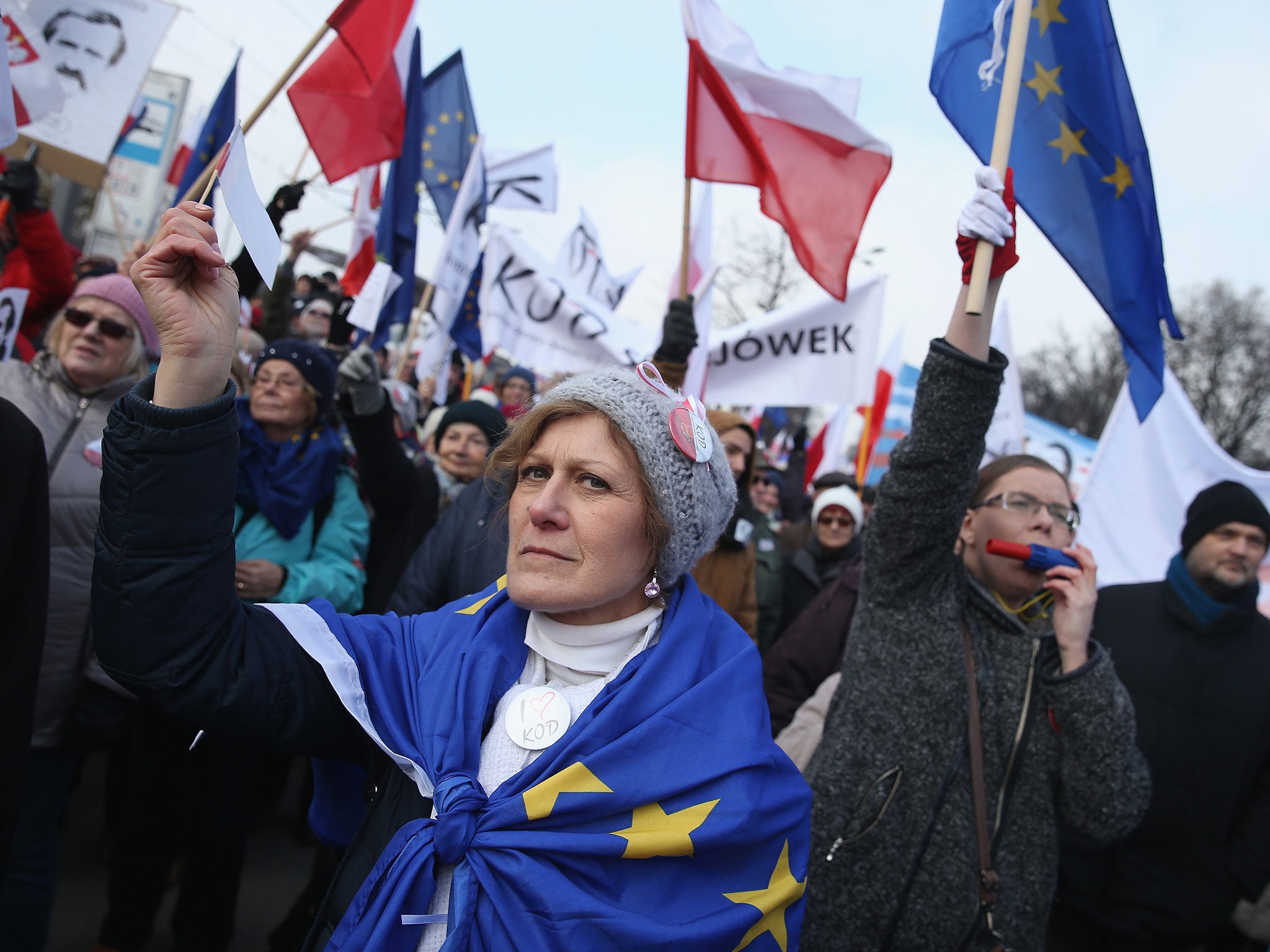 People wave Polish and European Union flags as they gather for a pro-democracy march in Warsaw