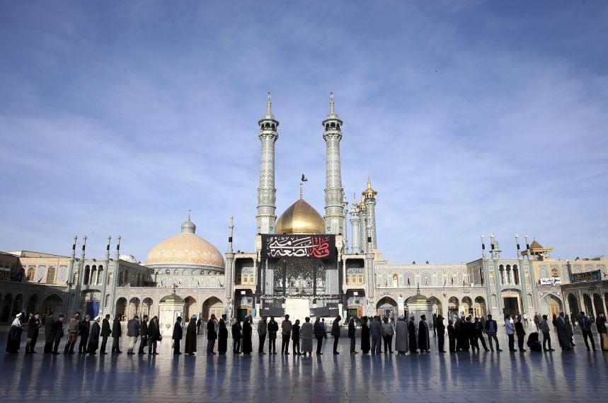 Iranians stand in line at a polling station in Qom