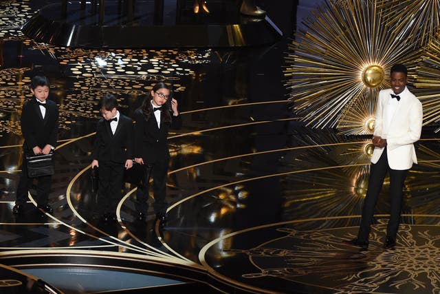 Actor Chris Rock presents children representing accountants from PricewaterhouseCoopers on stage at the  Oscars