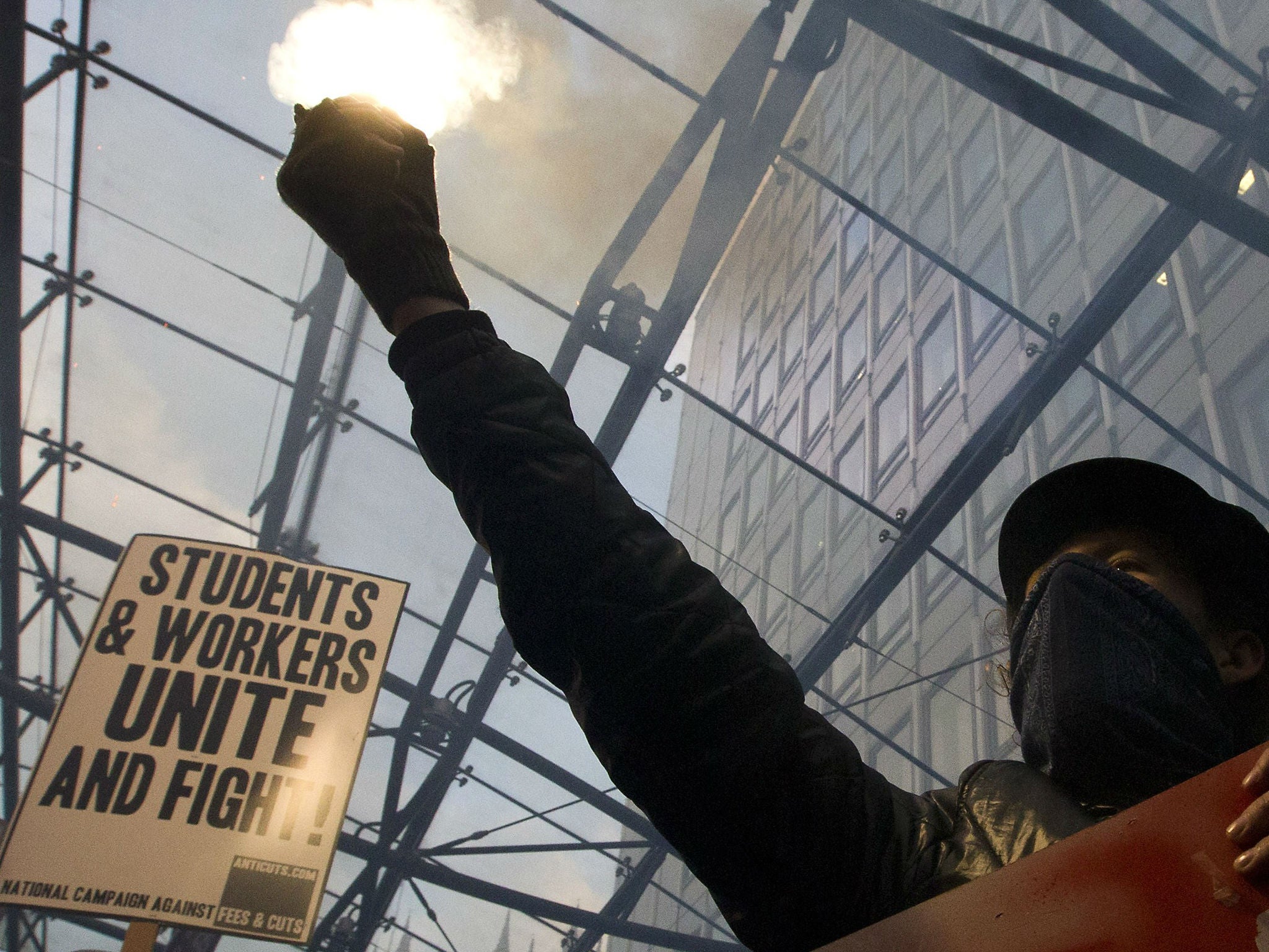 A masked protester holds a flare during a student march against university fees in London on November 19, 2014