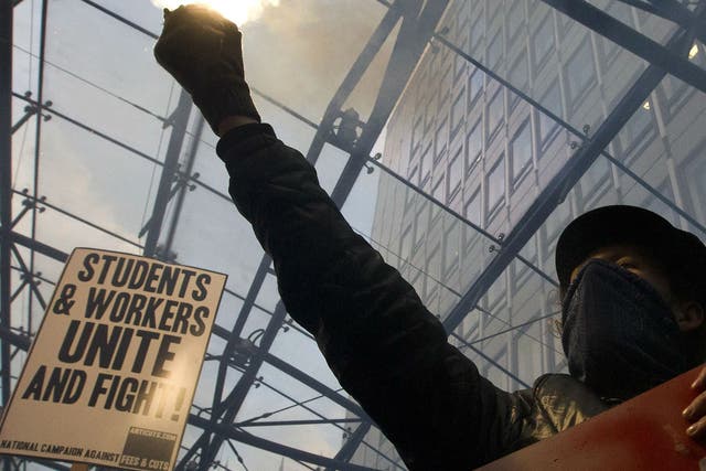 A masked protester holds a flare during a student march against university fees in London on November 19, 2014