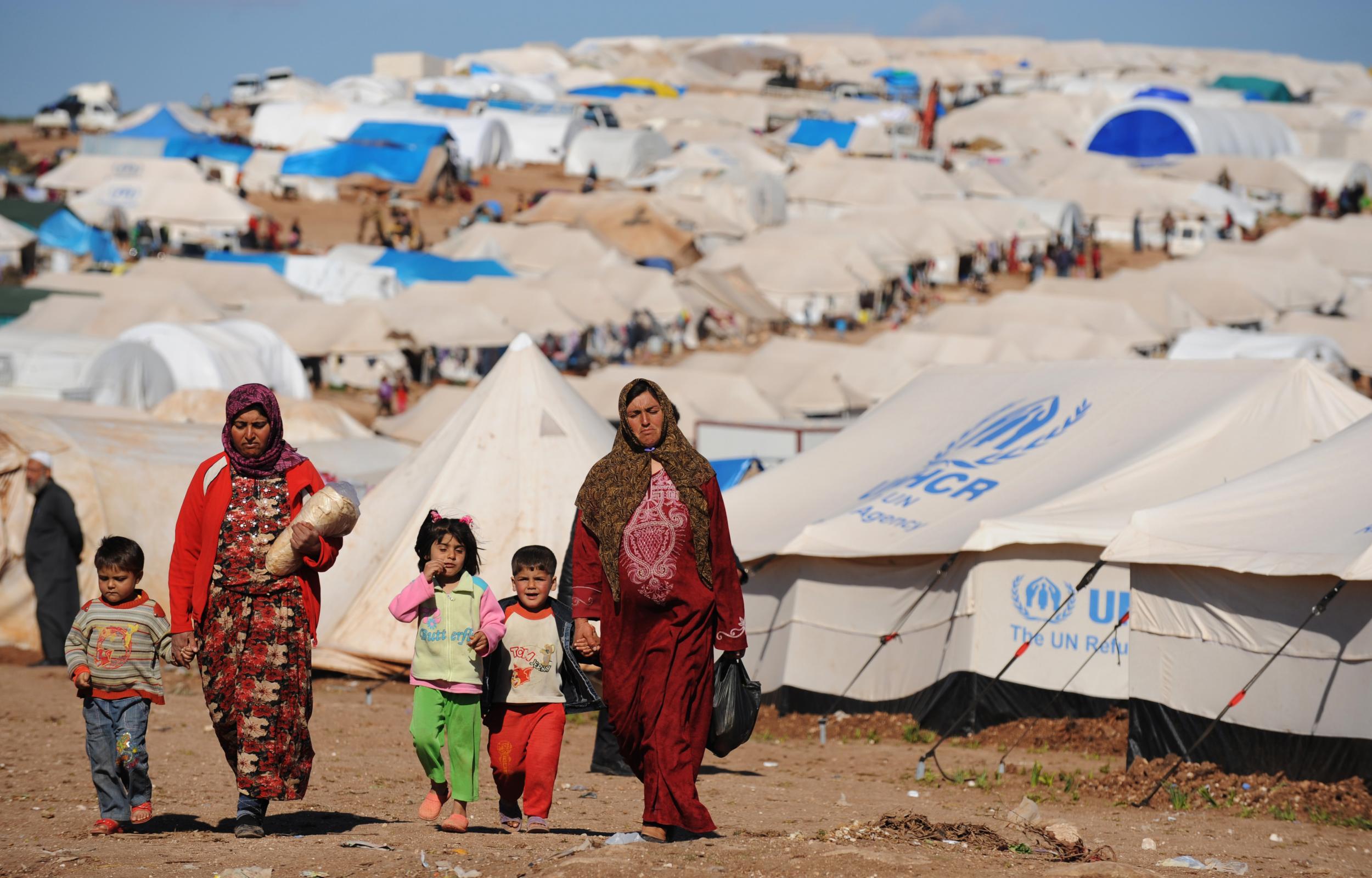 Syrian displaced people walk in the Atme camp, along the Turkish border in the northwestern Syrian province of Idlib