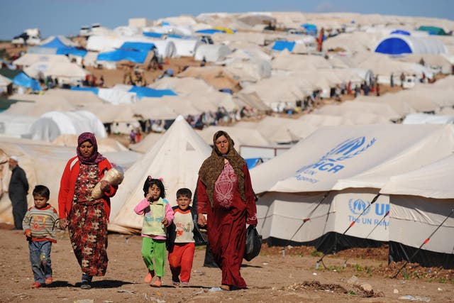 Syrian displaced people walk in the Atme camp, along the Turkish border in the northwestern Syrian province of Idlib