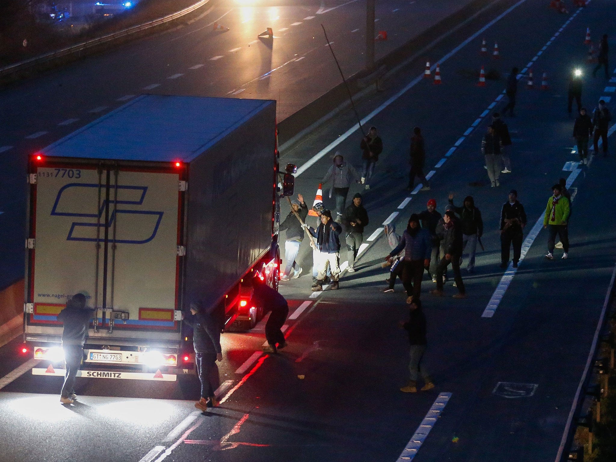 Refugees block a truck on the highway near the so-called Calais Jungle make-shift camp at the start of the expulsion of a part of 'the Jungle' in Calais, France, 29 February 2016