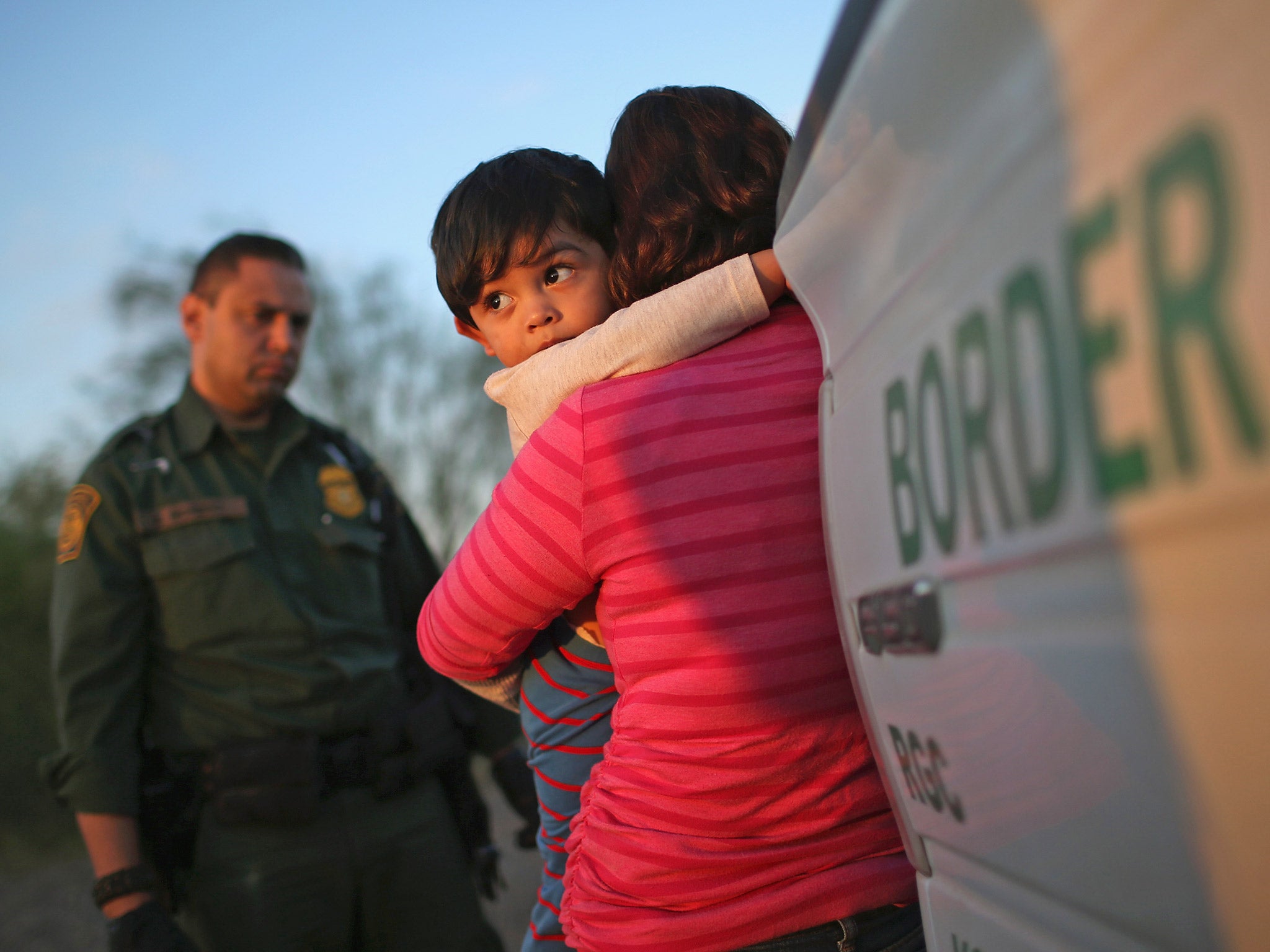 A mother and child are stopped by Border Patrol agents having just illegally crossed the US-Mexico border into Texas, near Rio Grande City, last December (Getty)