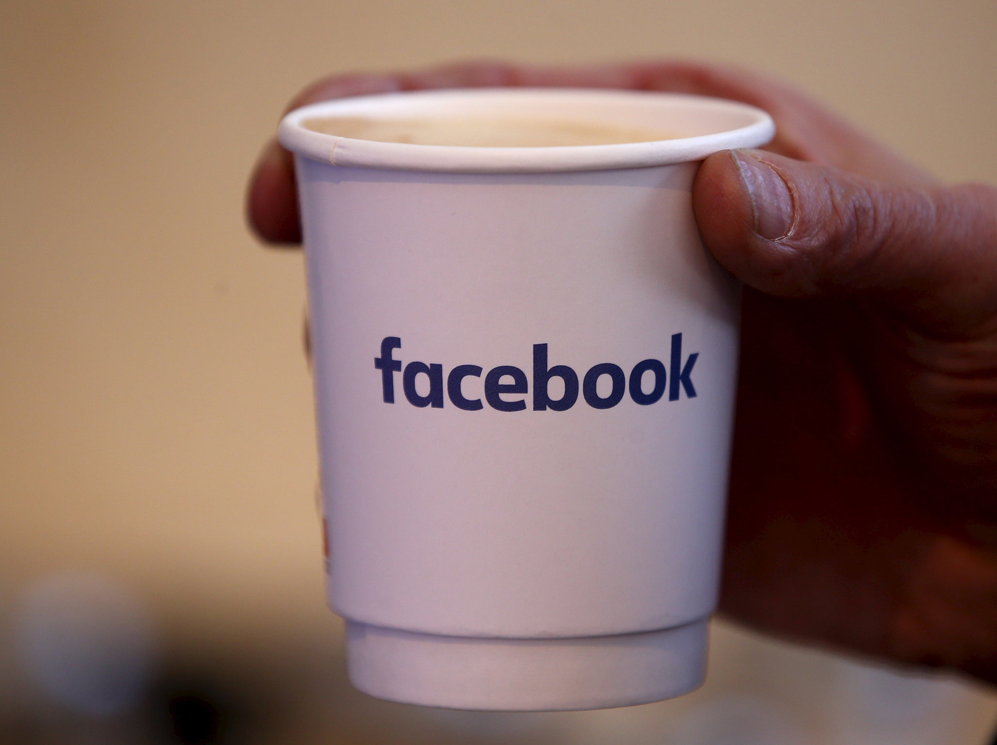 A journalist holds a cups with the Facebook logo at the new Facebook Innovation Hub during a preview media tour in Berlin, Germany, February 24, 2016