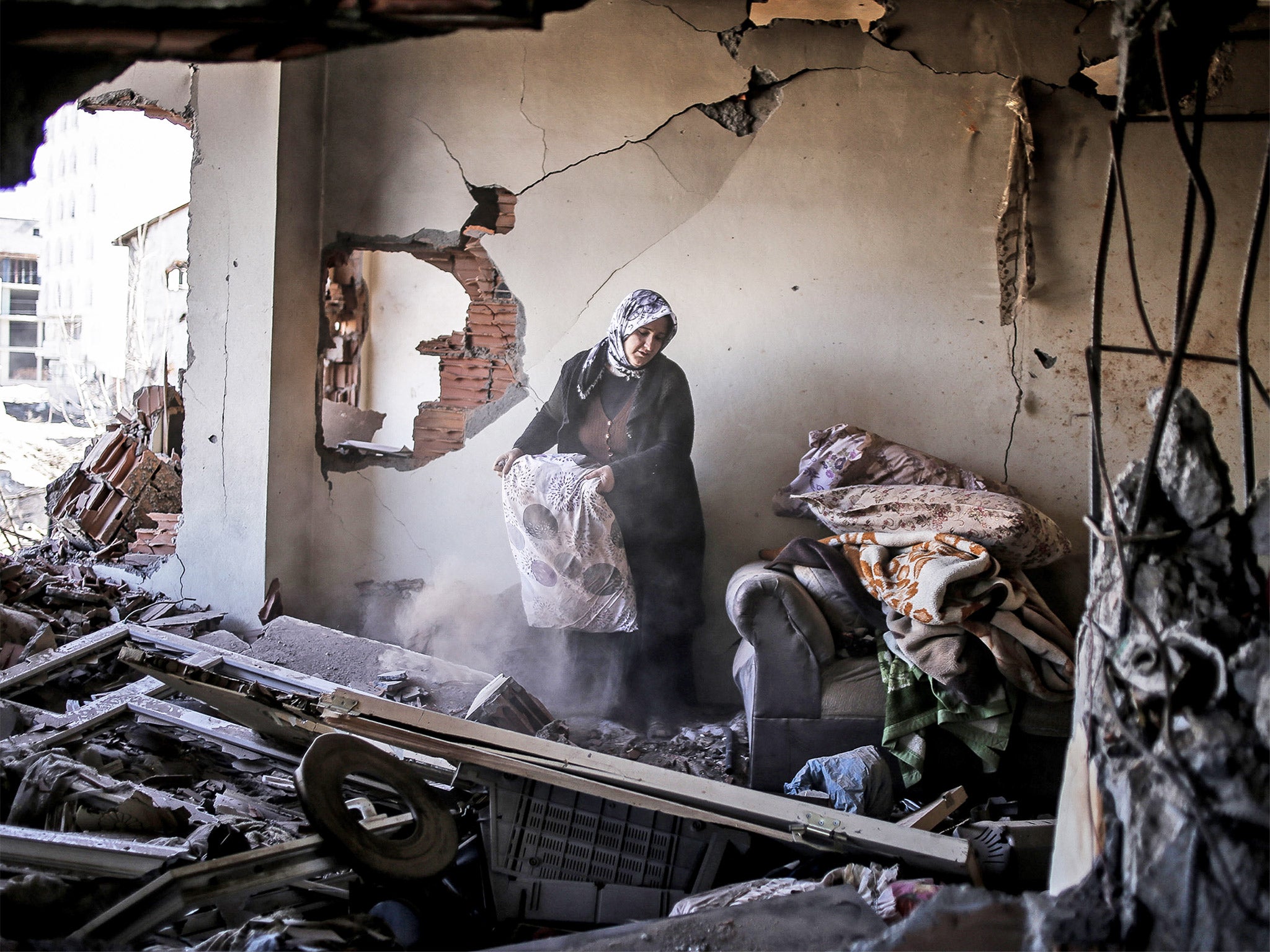 A woman inspects her belongings in her ruined home in Cizre. Turkish authorities have scaled down a 24-hour curfew imposed on the mainly Kurdish town (Getty_