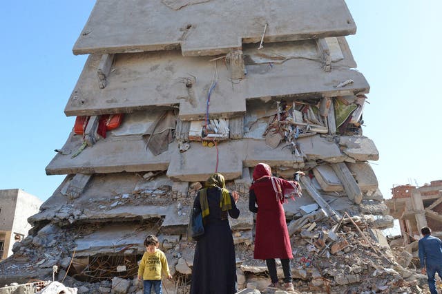 A family stands among the rubble of damaged buildings following heavy fighting in Cizre