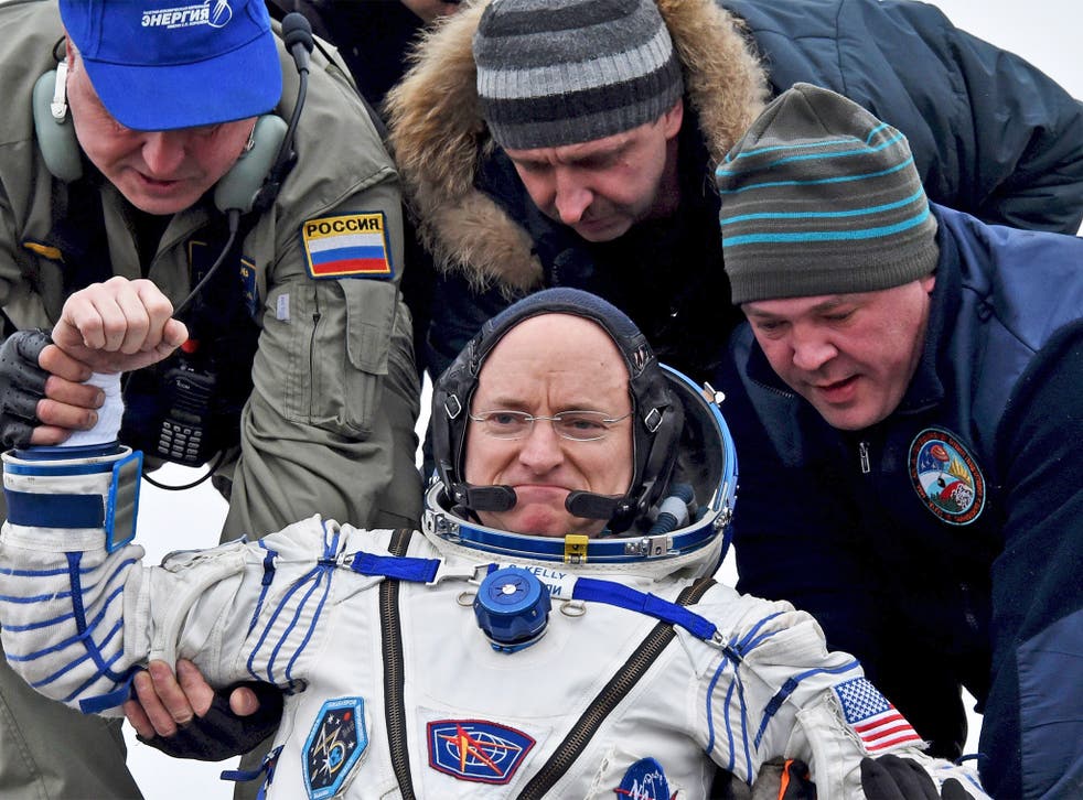 Ground personnel help US astronaut Scott Kelly out of the Soyuz capsule, shortly after it landed near the town of Jezkazgan in Kazakhstan, yesterday. Commander Kelly was immediately put through a number of physical tests