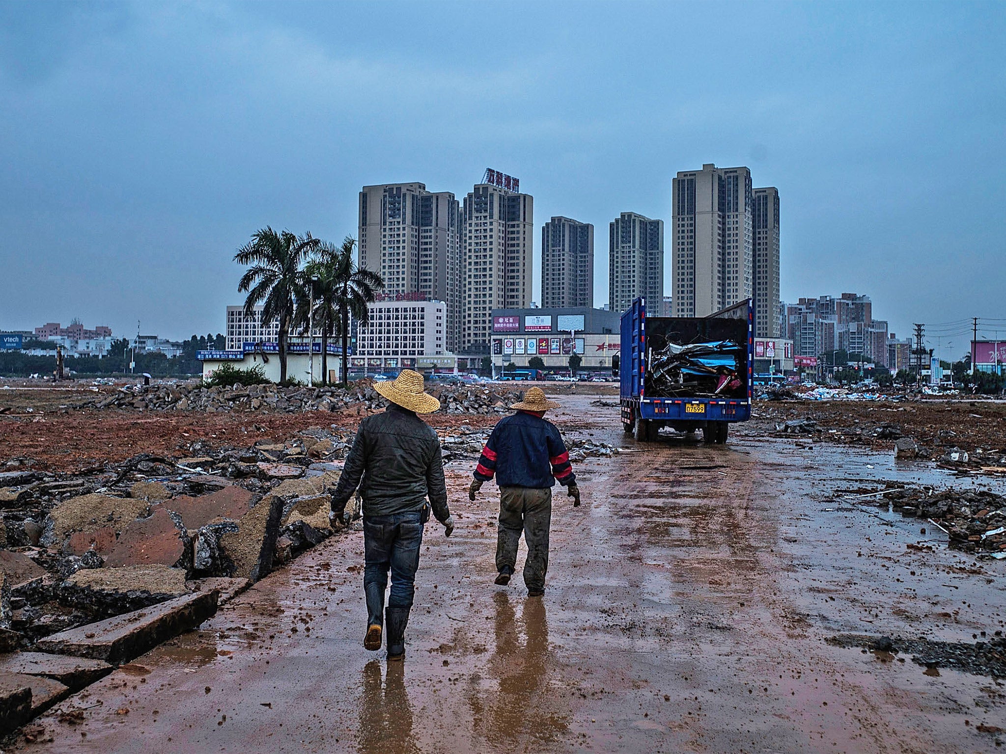 Workers walk past demolished factories in the once-thriving industrial town of Houjie, in Guangdong province