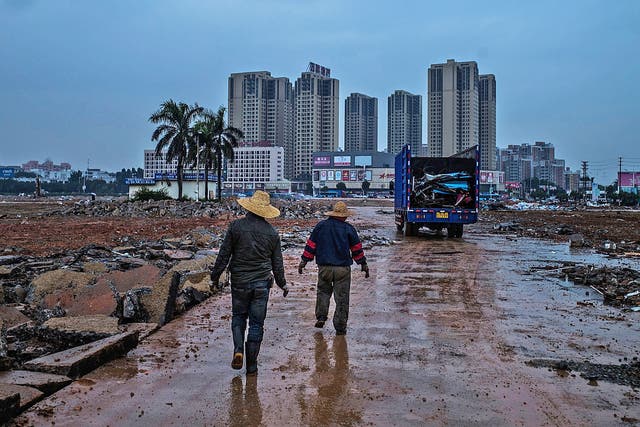 Workers walk past demolished factories in the once-thriving industrial town of Houjie, in Guangdong province