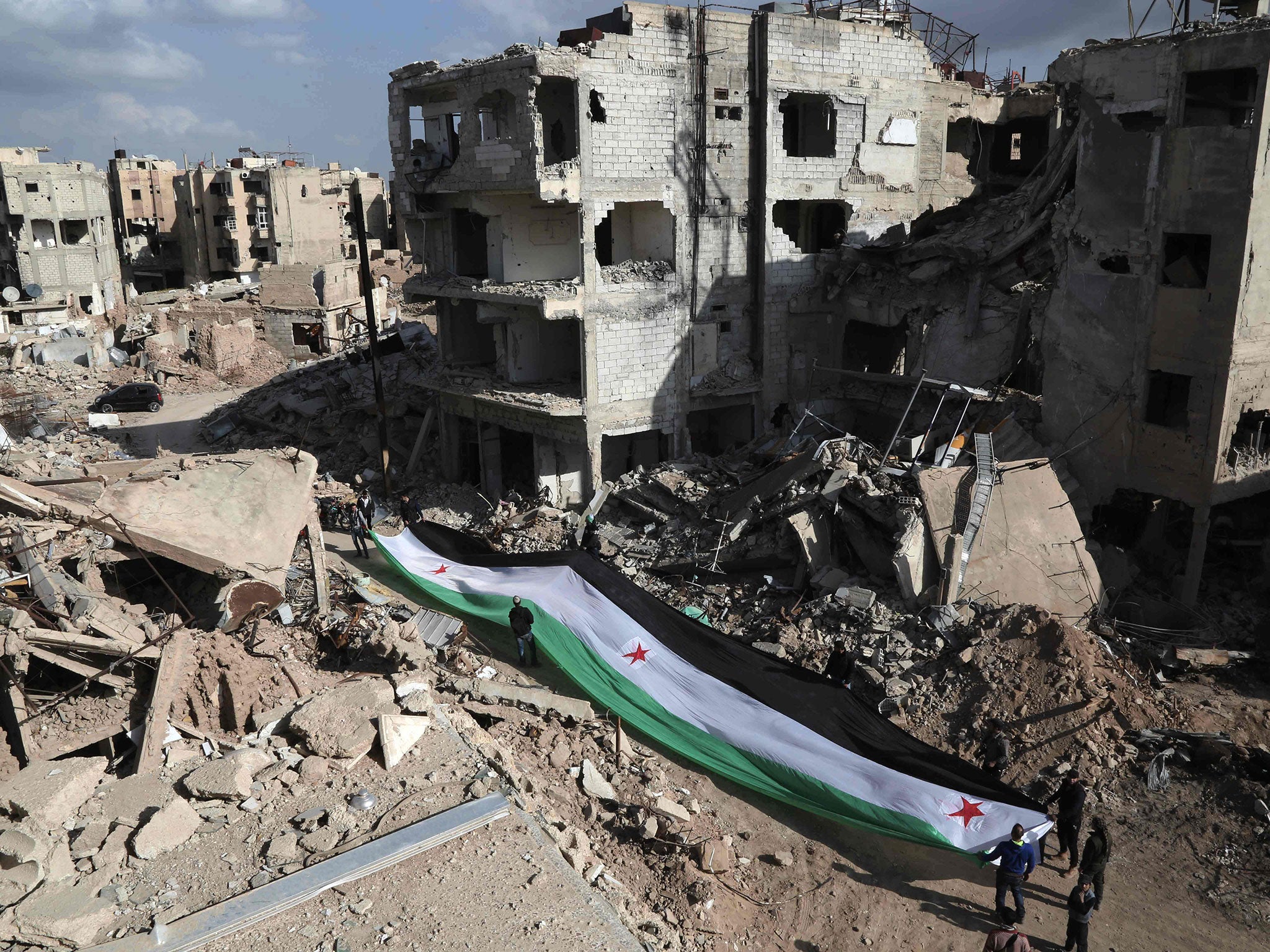 Activists hold a pre-Assad Syrian flag in Jabar, Damascus