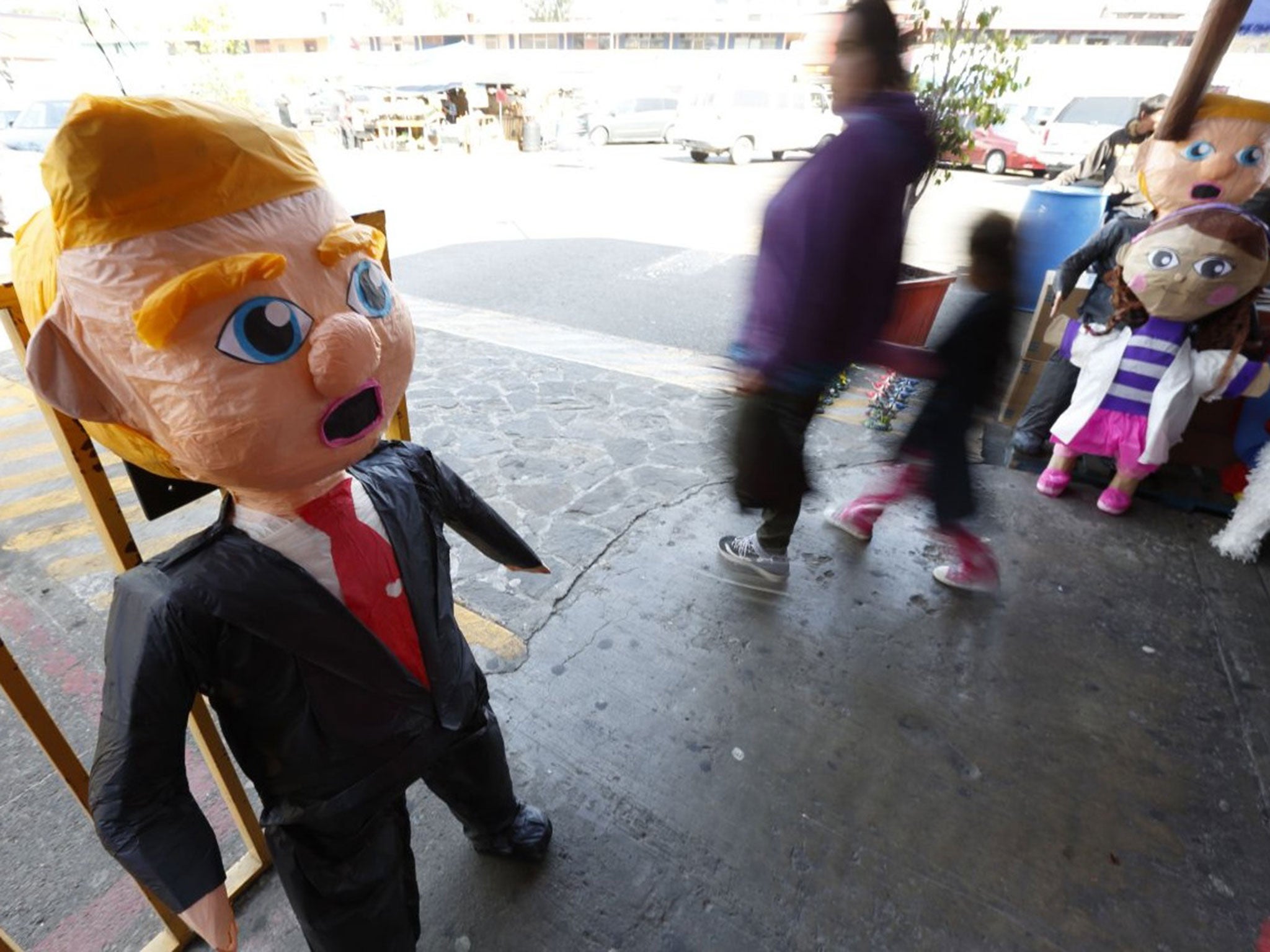 People pass a pinata in the image of Republican presidential candidate Donald Trump in Tijuana, Mexico