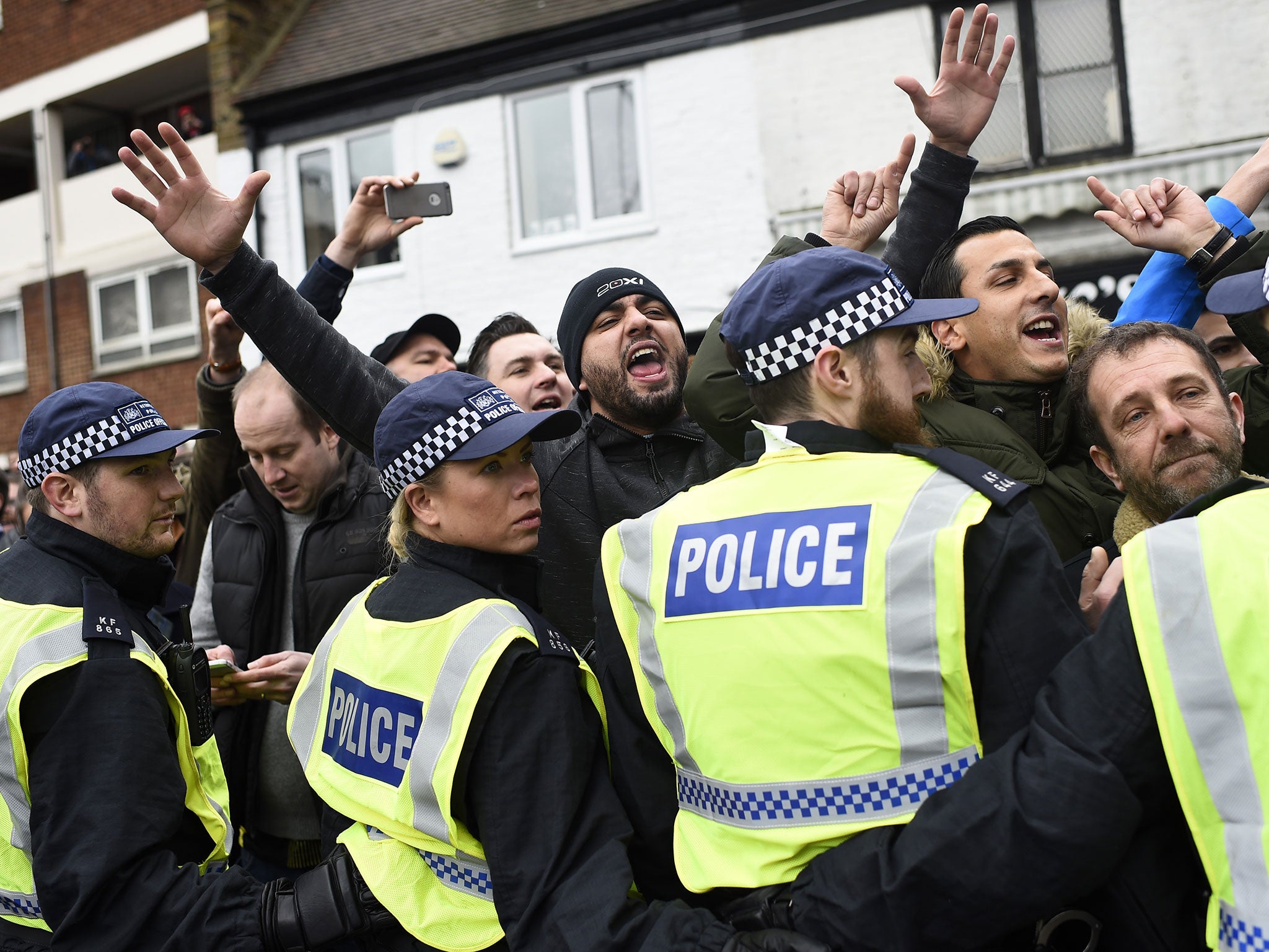 Police hold back chanting supporters ahead of the match