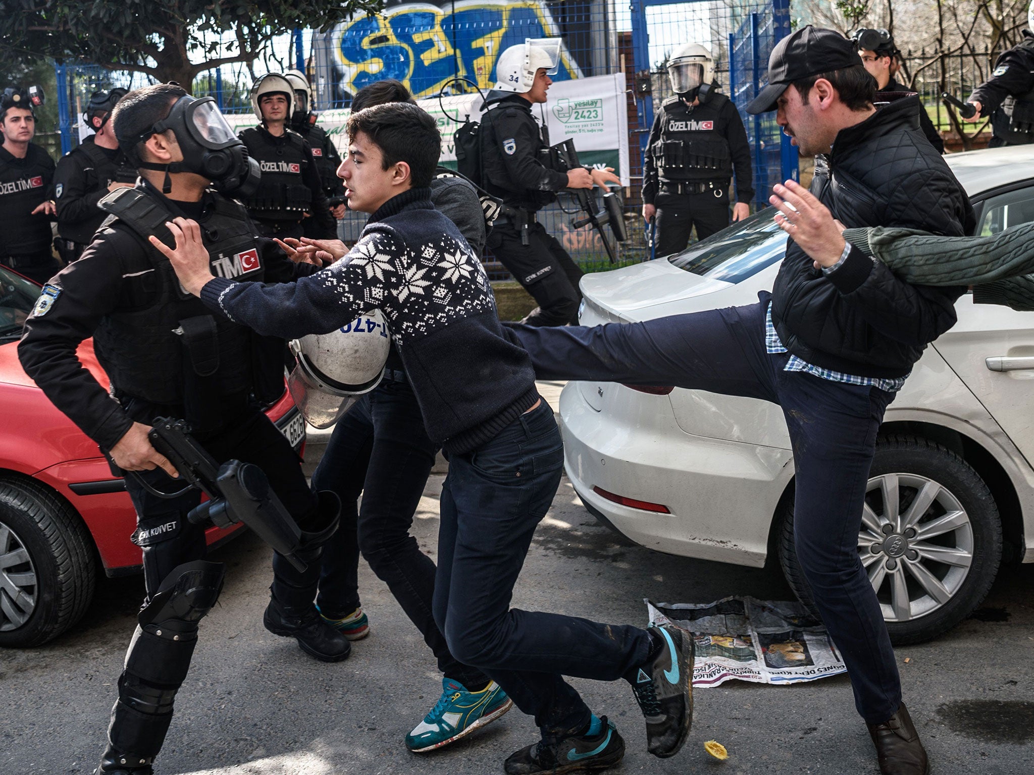 A plainclothes police officer kicks a demonstrator as Turkish anti-riot police officers disperse supporters in front of the headquarters of the Turkish daily newspaper Zaman in Istanbul on March 5, 2016