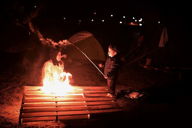 A boy plays with a stick by a bonfire at the makeshift refugee camp near the village of Idomeni, where thousands of migrants and refugees  are stranded