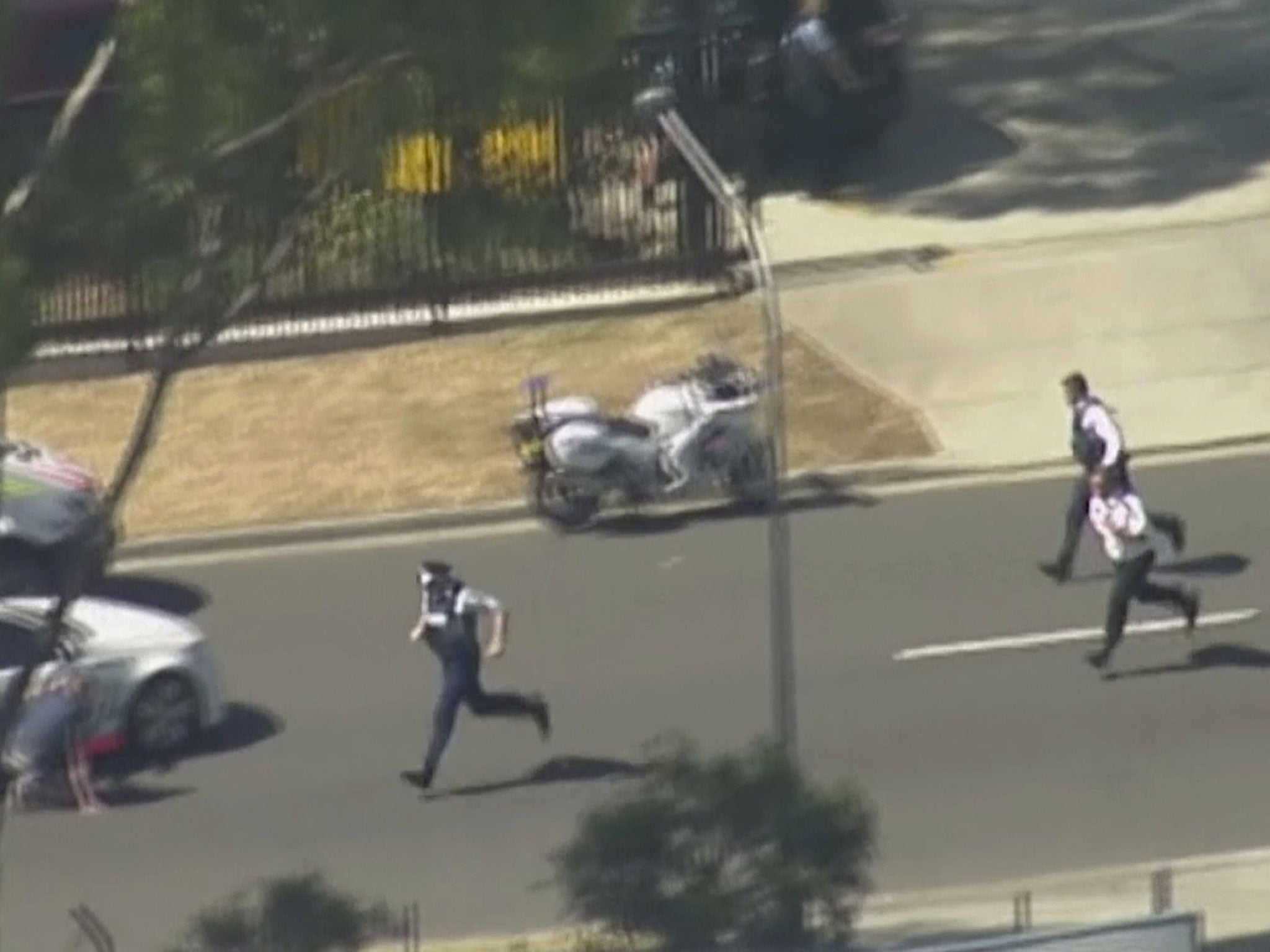 In this image made from video provided by Channel 7 Australia, police run to take position in Ingleburn, an industrial section of Sydney, as they respond to a shooting