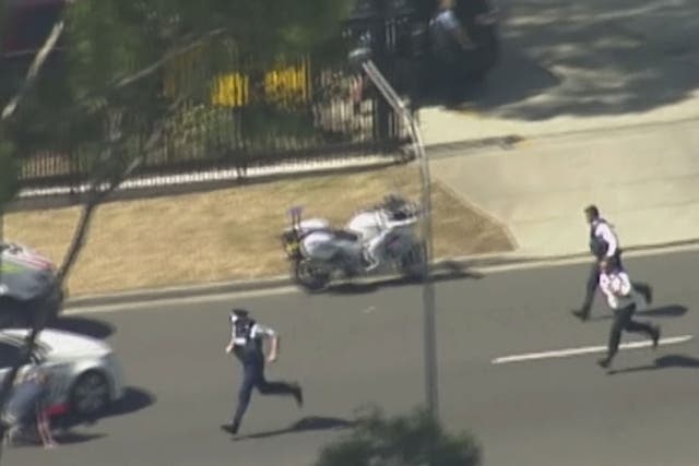 In this image made from video provided by Channel 7 Australia, police run to take position in Ingleburn, an industrial section of Sydney, as they respond to a shooting