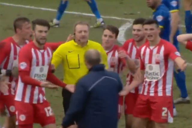 The Accrington players surround the referee to protest as manager John Coleman attempts to calm them