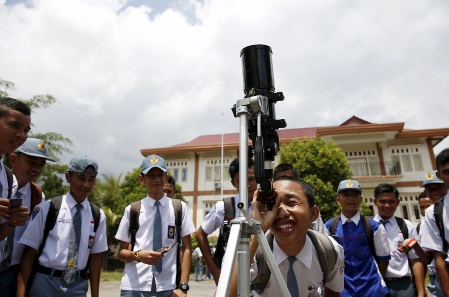 A schoolboy observes the Sun through a telescope in Ternate island, Indonesia, ahead of the eclipse (Pic: Beawiharta/Reuters)