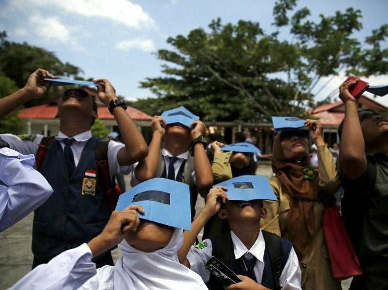 Students and teachers test their homemade eclipse glasses on the island of Ternate, Indonesia