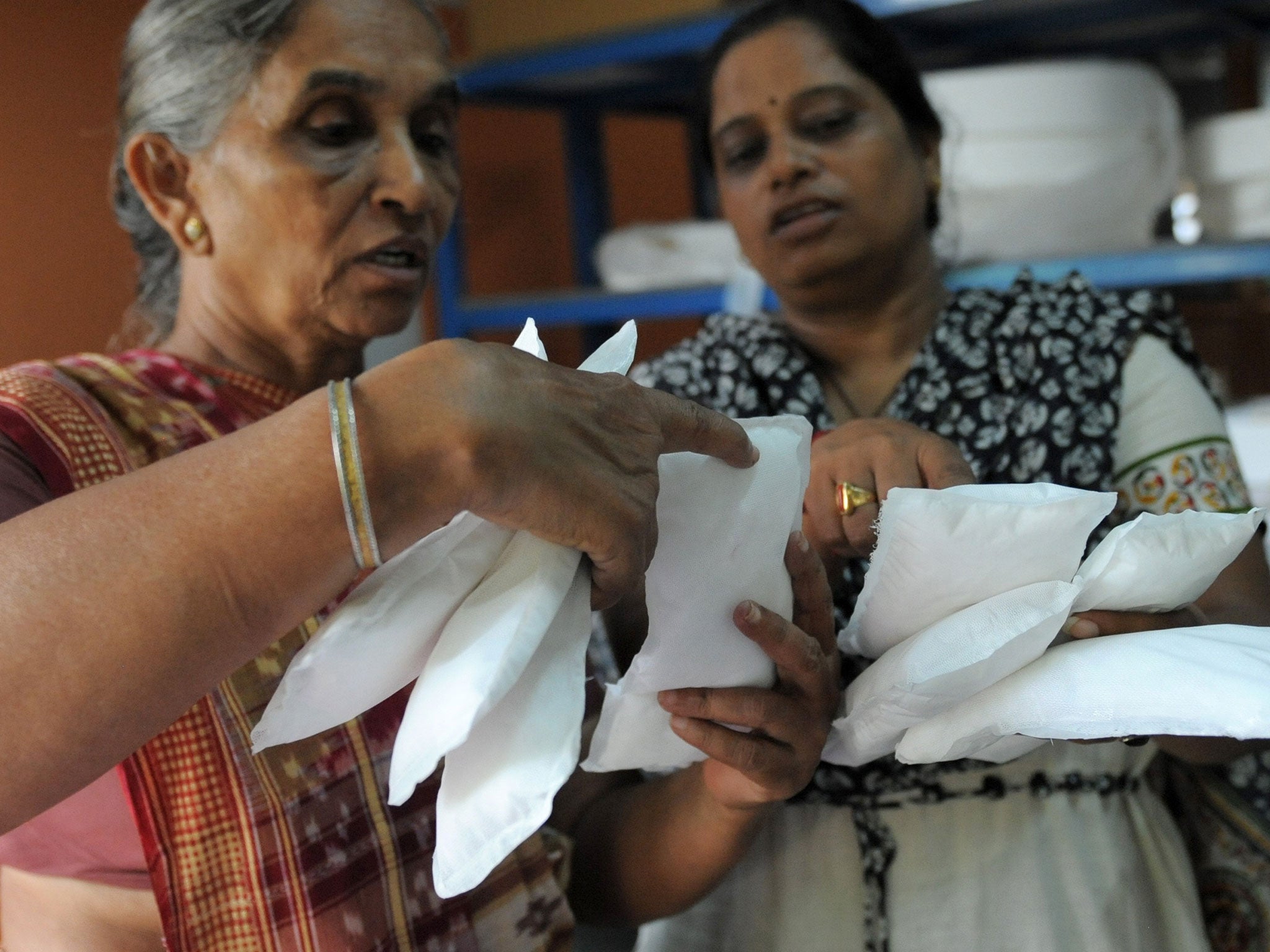 Savitaben Patel, CEO of Self Employed Women's Association (SEWA) and Assistant Project Manager, Nilam Solanki (R) check the quality of low cost sanitary pads made by members at their facility