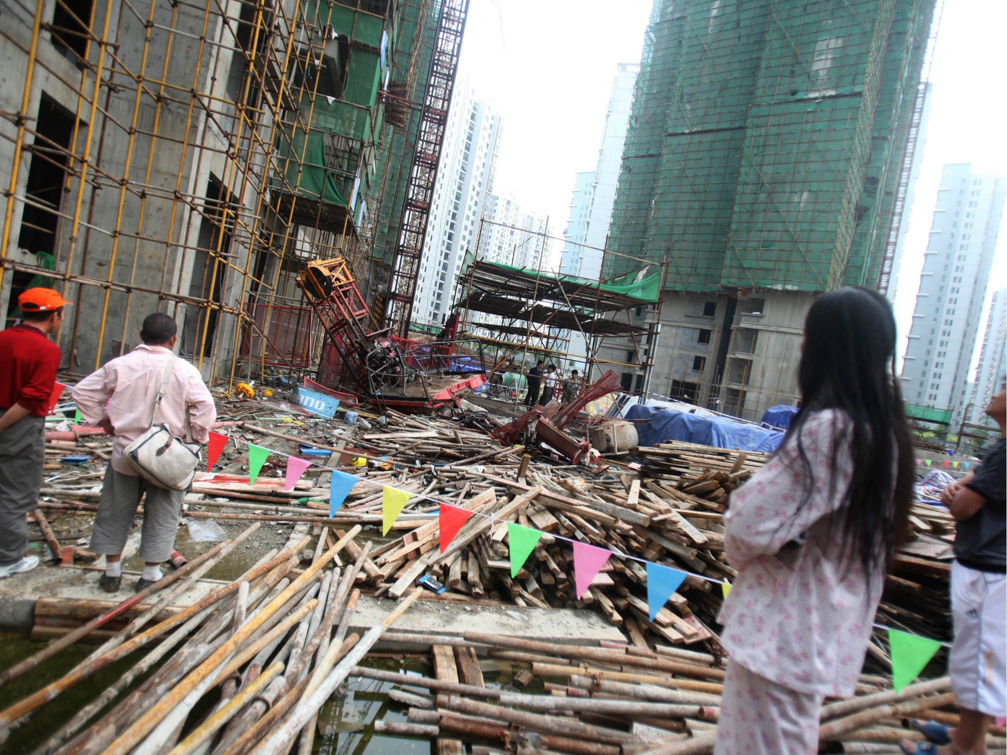 People gather to watch after a construction lift at a housing compound currently under construction crashed in Wuhan, central China's Hubei province on September 13, 2012