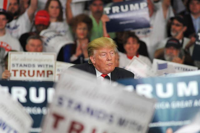 Donald Trumps is surrounded by signs of supporters as he speaks at Madison Central High School during at a campaign rally in Madison, Mississippi.