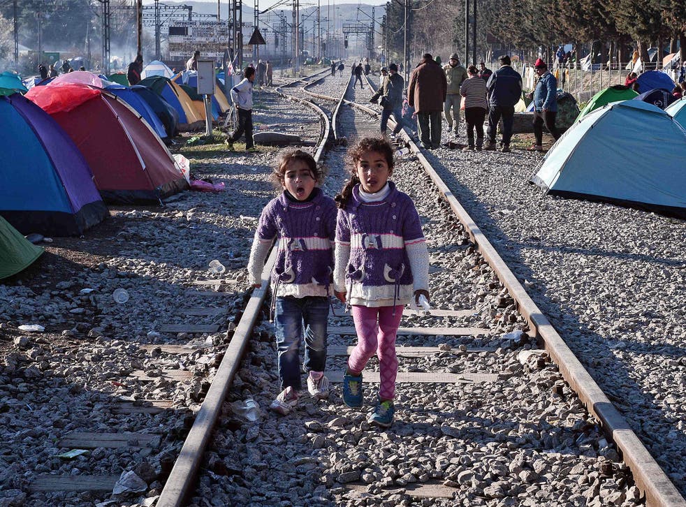 Sisters walk on railway tracks where refugees installed their tents at the makeshift camp of the Greek-Macedonian border near the Greek village of Idomeni, on March 5, 2016