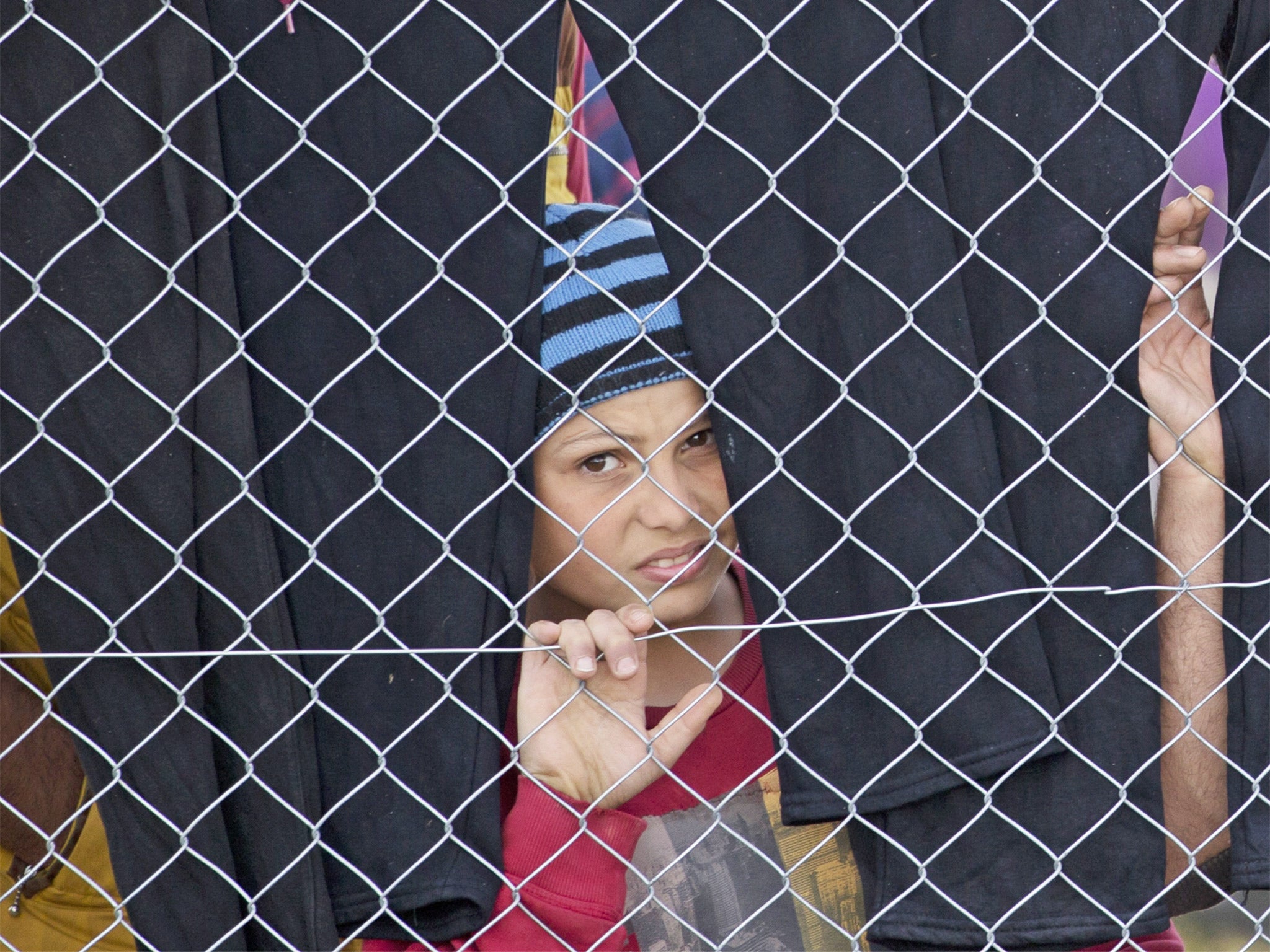 A boy peers through a fence at the northern Greek border station of Idomeni