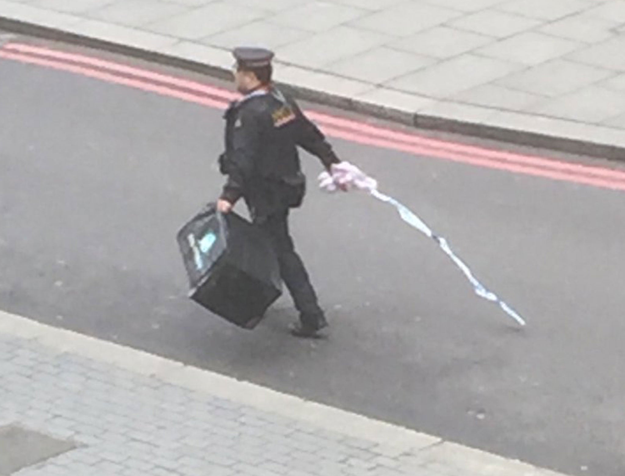 A police officer carries what appears to be a Deliveroo bag after a 'suspect package' caused streets in central London to be cordoned off -Photo Ben Longstaff/Twitter