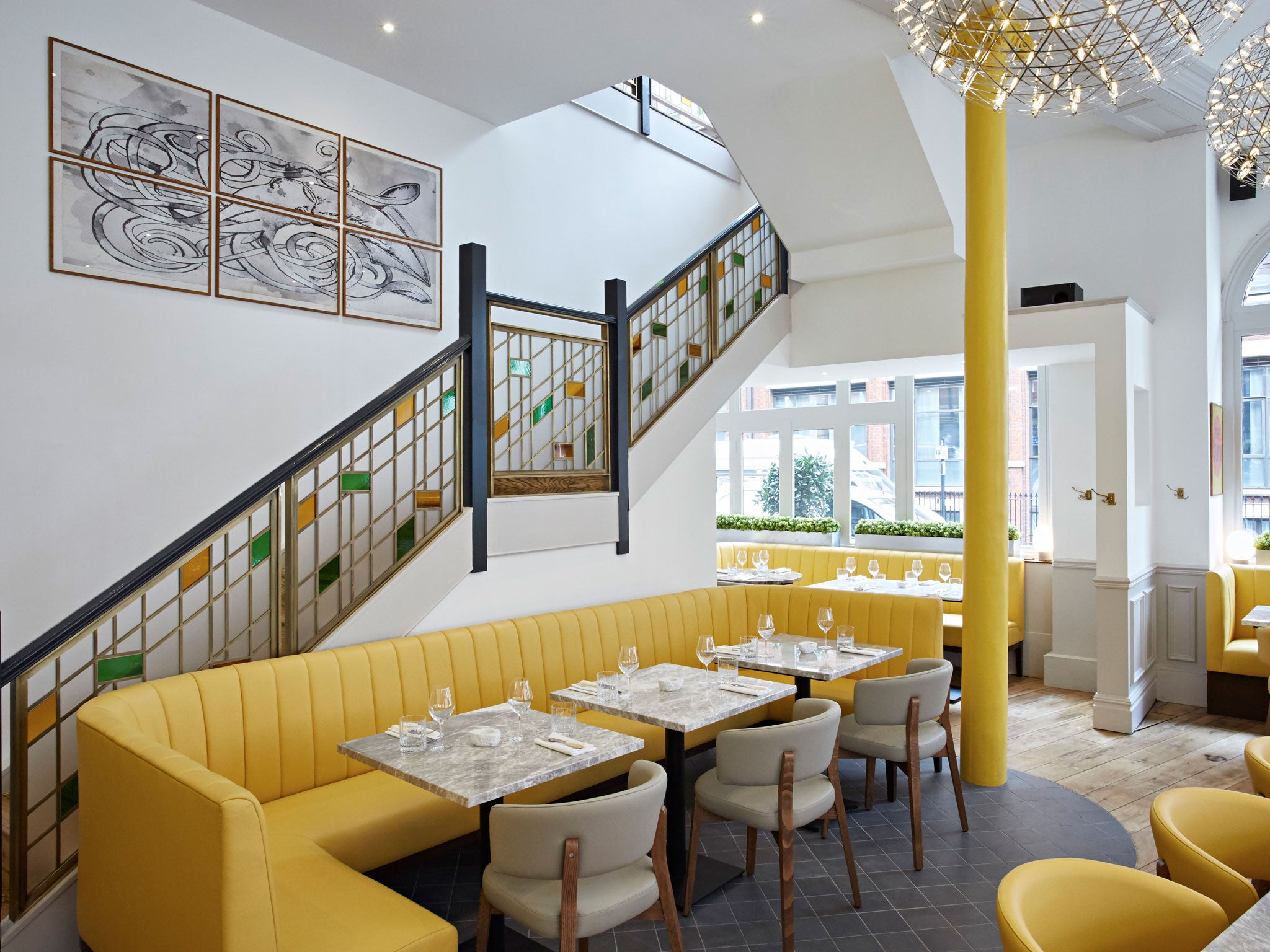 The dining room is fabulously light and airy, with white walls, table and chairs, wooden floors and banana-yellow seating