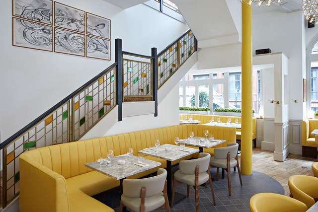 The dining room is fabulously light and airy, with white walls, table and chairs, wooden floors and banana-yellow seating