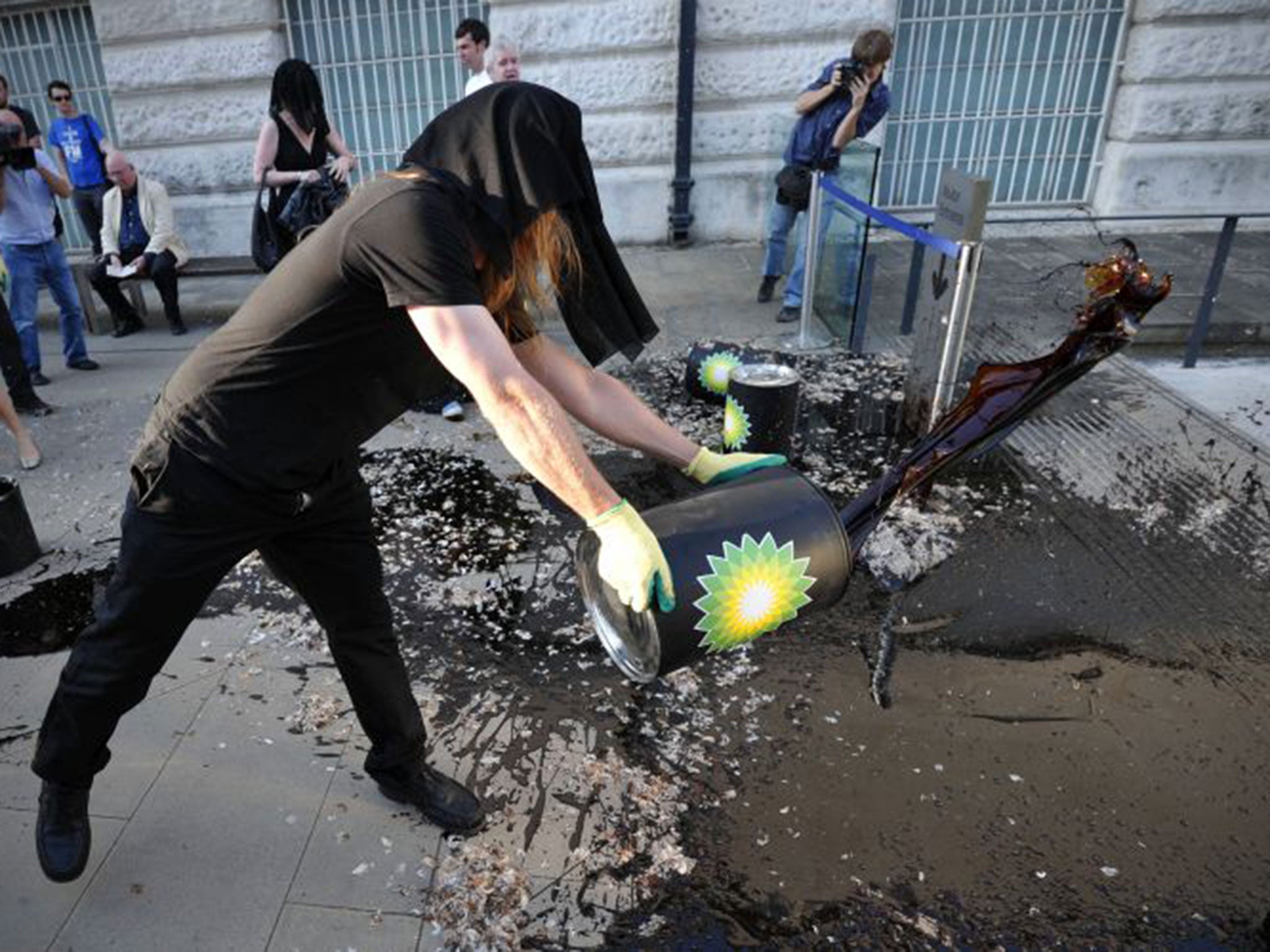 A protester dumps oil-like molasses at Tate Britain in 2010