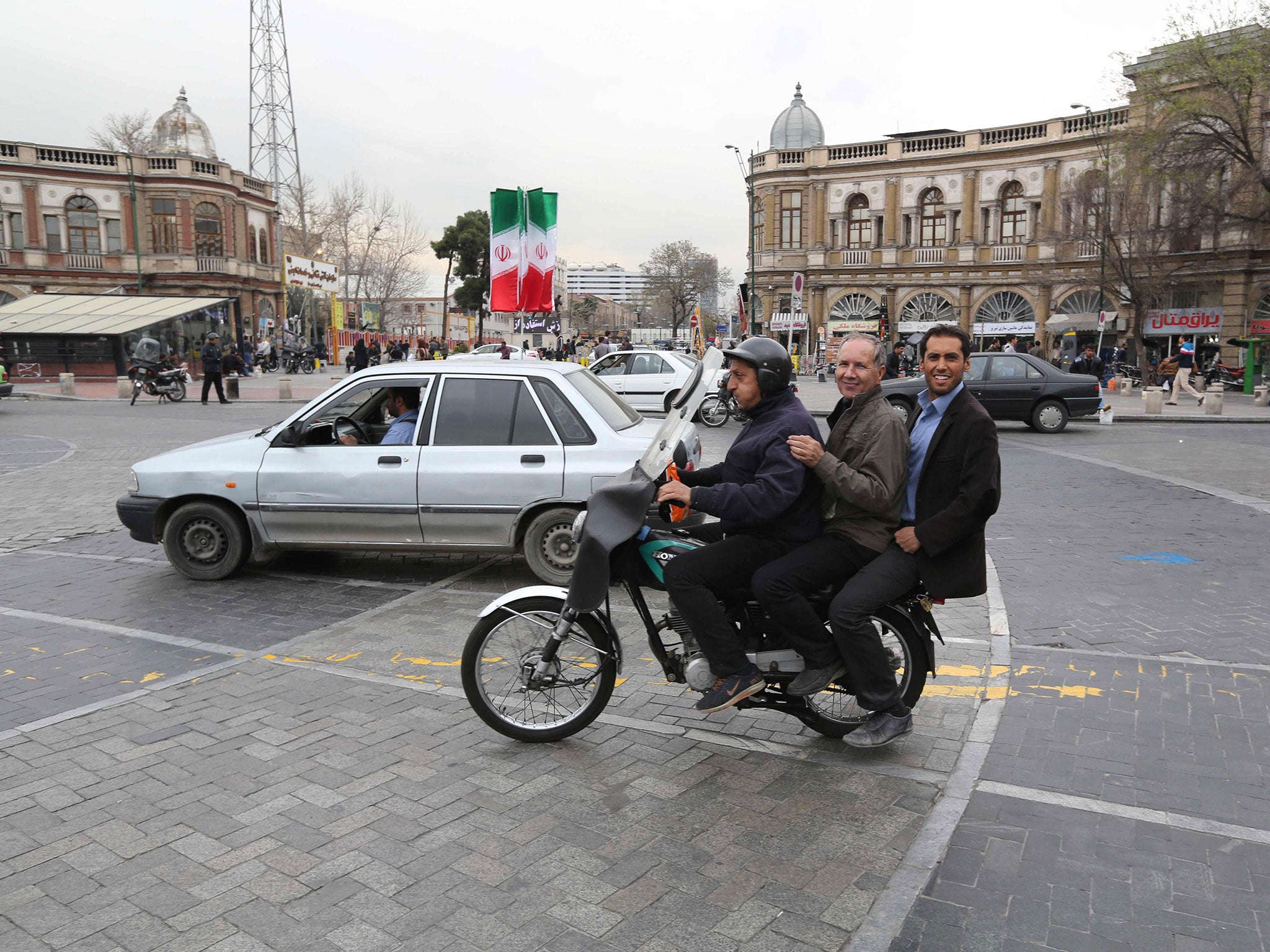 Iranian men take a ride on a motorcycle taxi in central Tehran