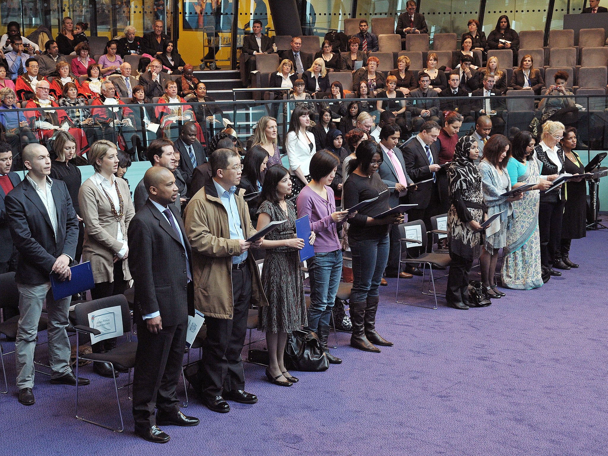Immigrants to the UK take an oath before being presented with a certificate of citizenship during a 'Citizenship Ceremony' at City Hall, London