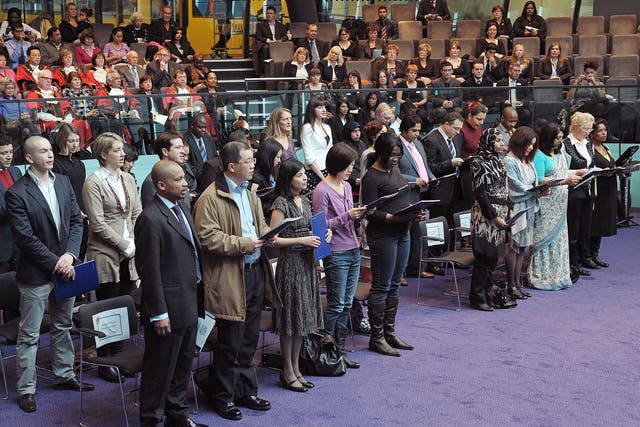 Immigrants to the UK take an oath before being presented with a certificate of citizenship during a 'Citizenship Ceremony' at City Hall, London