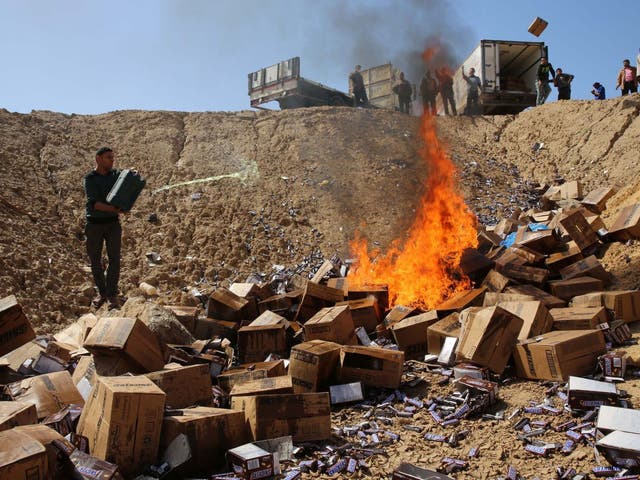 Palestinian worker throws gasoline on buringing boxes of Snickers chocolate on the outskirts of Gaza City, Thursday, March 10, 2016.
