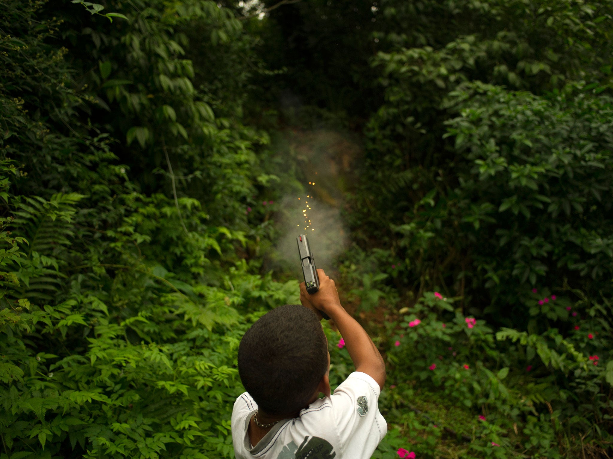 An 11-year-old boy, member of an armed criminal faction in Sao Paulo, learns how to shoot a 9mm automatic handgun, May 2013 © André Liohn/Prospekt