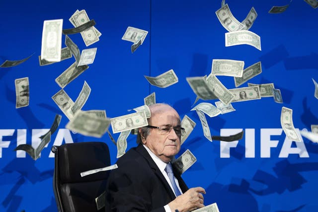 The then president of world football is showered with fake money in a satirical stunt by comedian Lee Nelson in Zurich last year