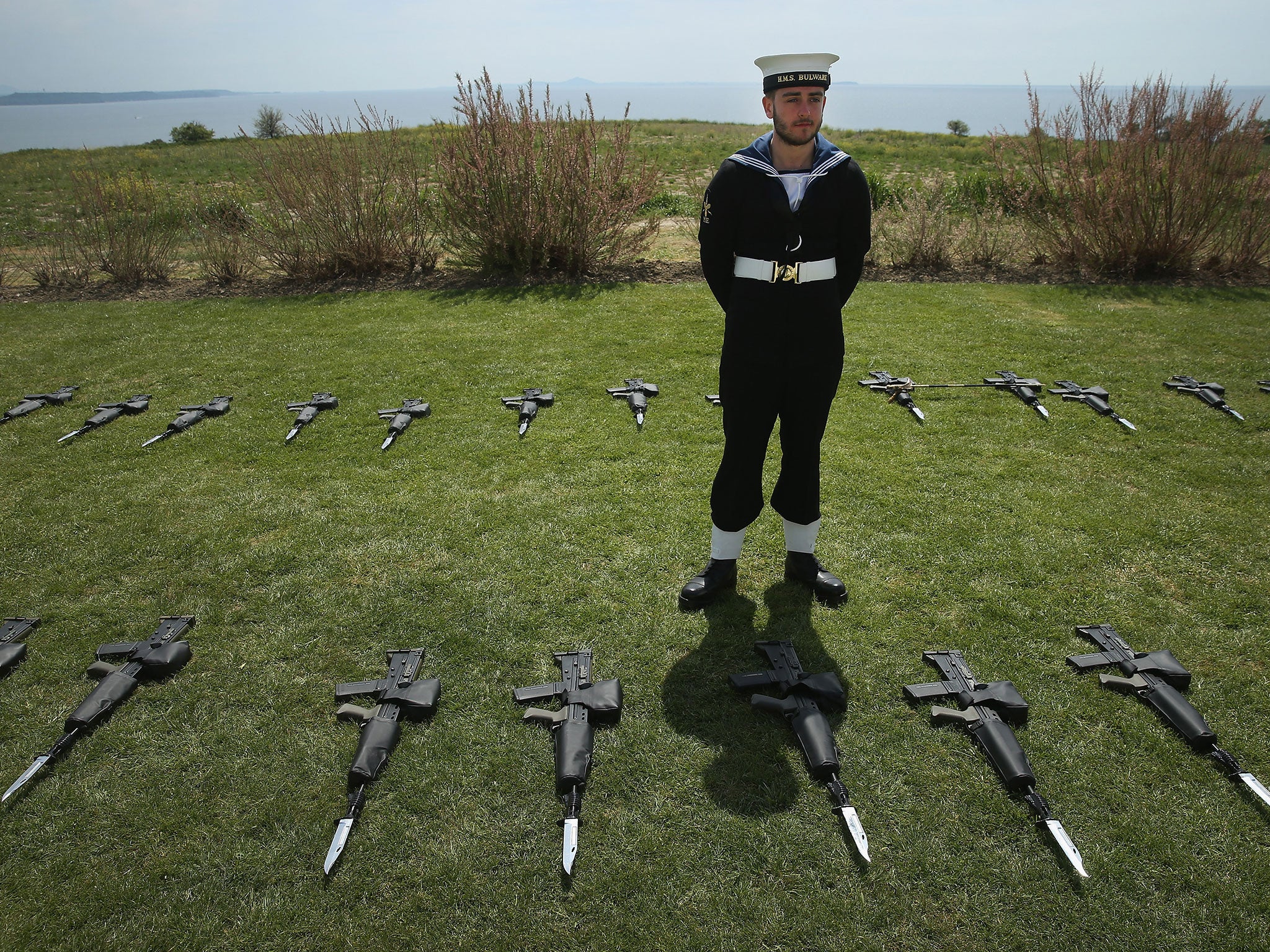 A member of the British Navy stands among SA-80 machine guns at the Helles Memorial, Turkey