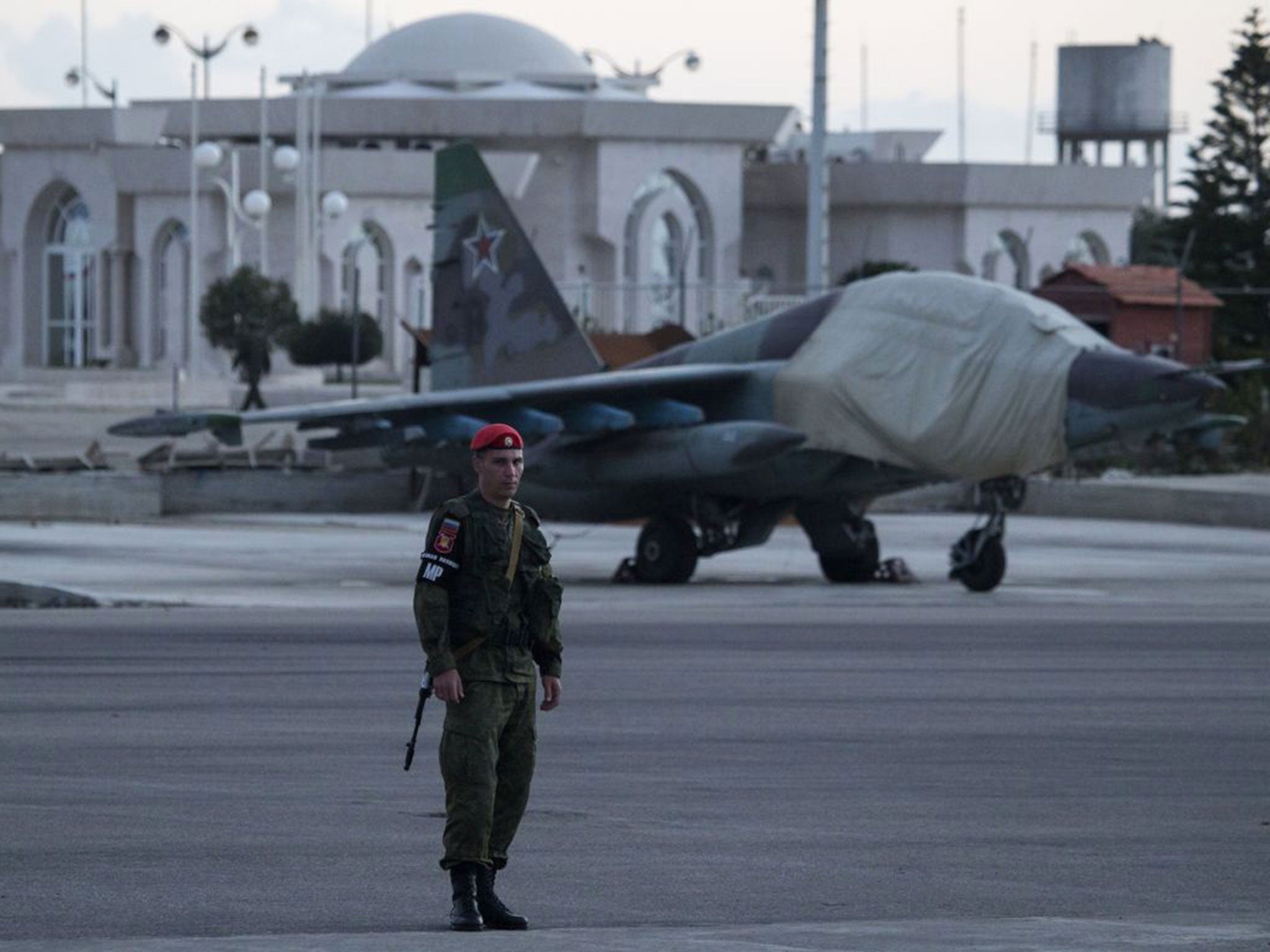 A Russian soldier guards a jet parked at Hemeimeem air base in Syria. Russian warplanes have mostly stayed on the ground since the cease-fire began