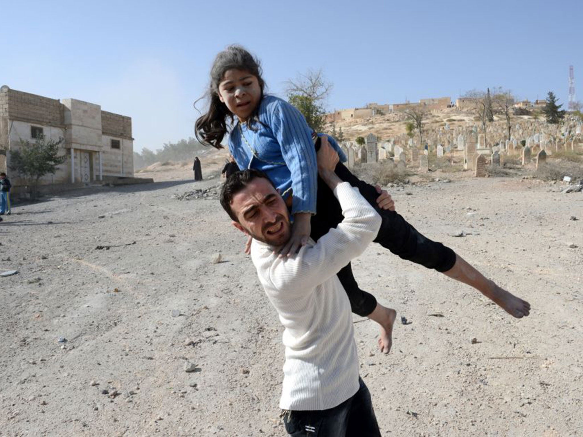 &#13;
A man carries a girl injured during a government air strike on al-Bab in 2012 &#13;