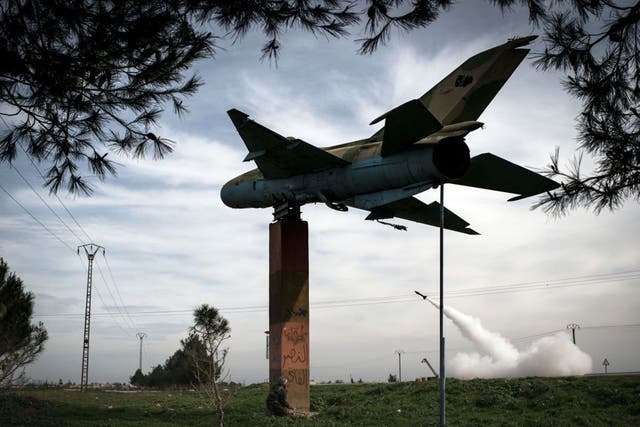 A man shelters beneath the gate guardian at Kwiriss airport in Al-Bab as rebels fire rockets at regime forces in February 2013